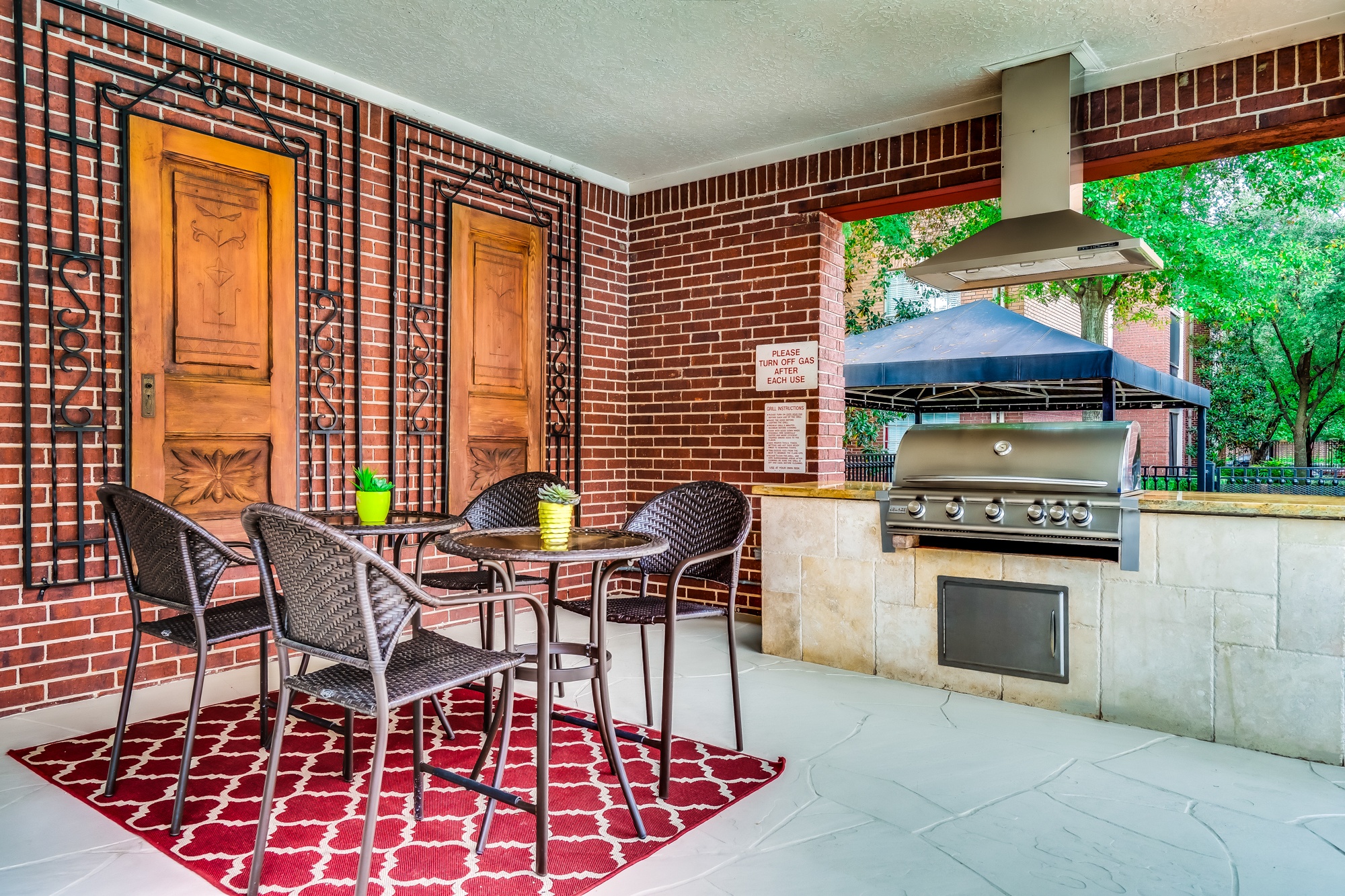 A patio with a table and chairs and a grill.